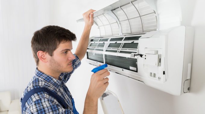 A Person Holding A Spray Towards The Air Conditioner